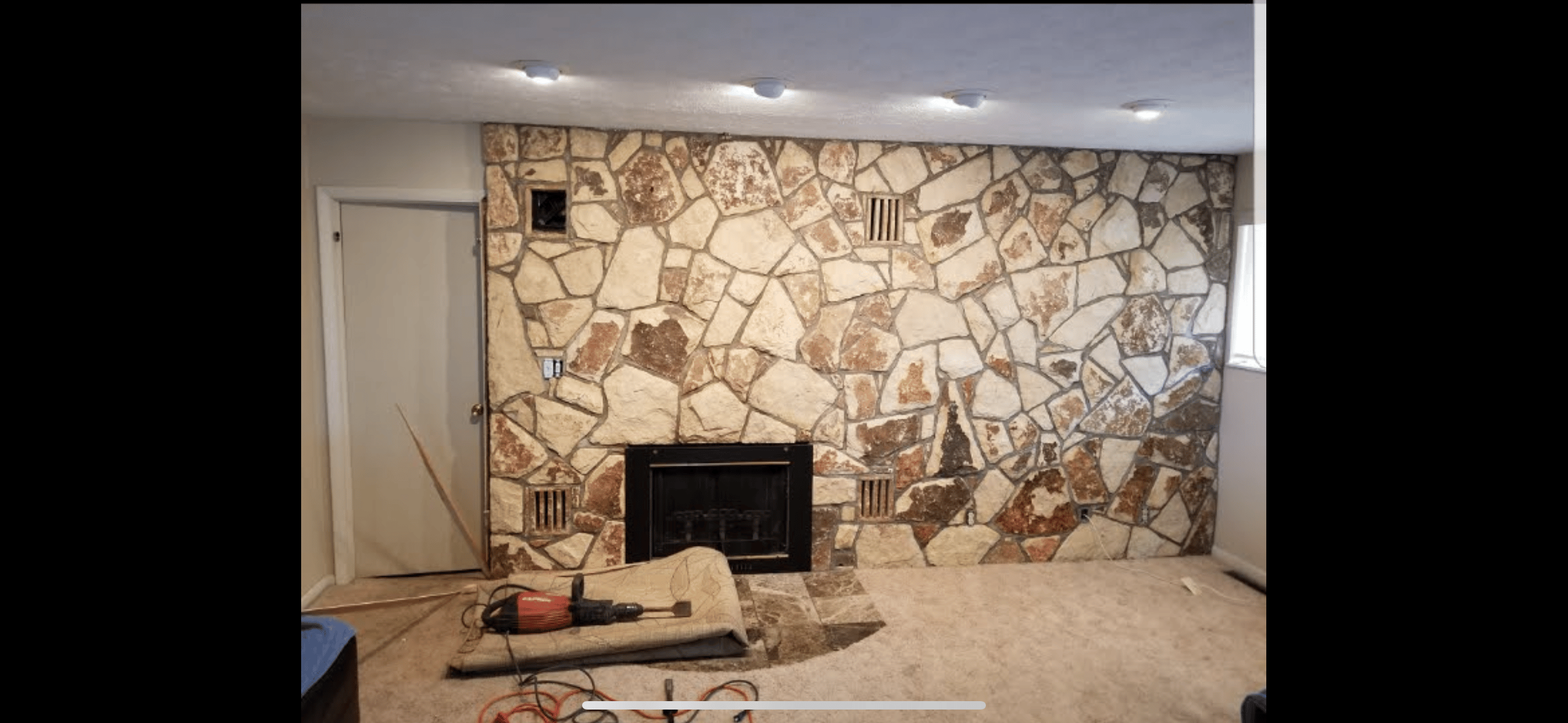 Living room before renovation showing outdated fireplace and worn carpet